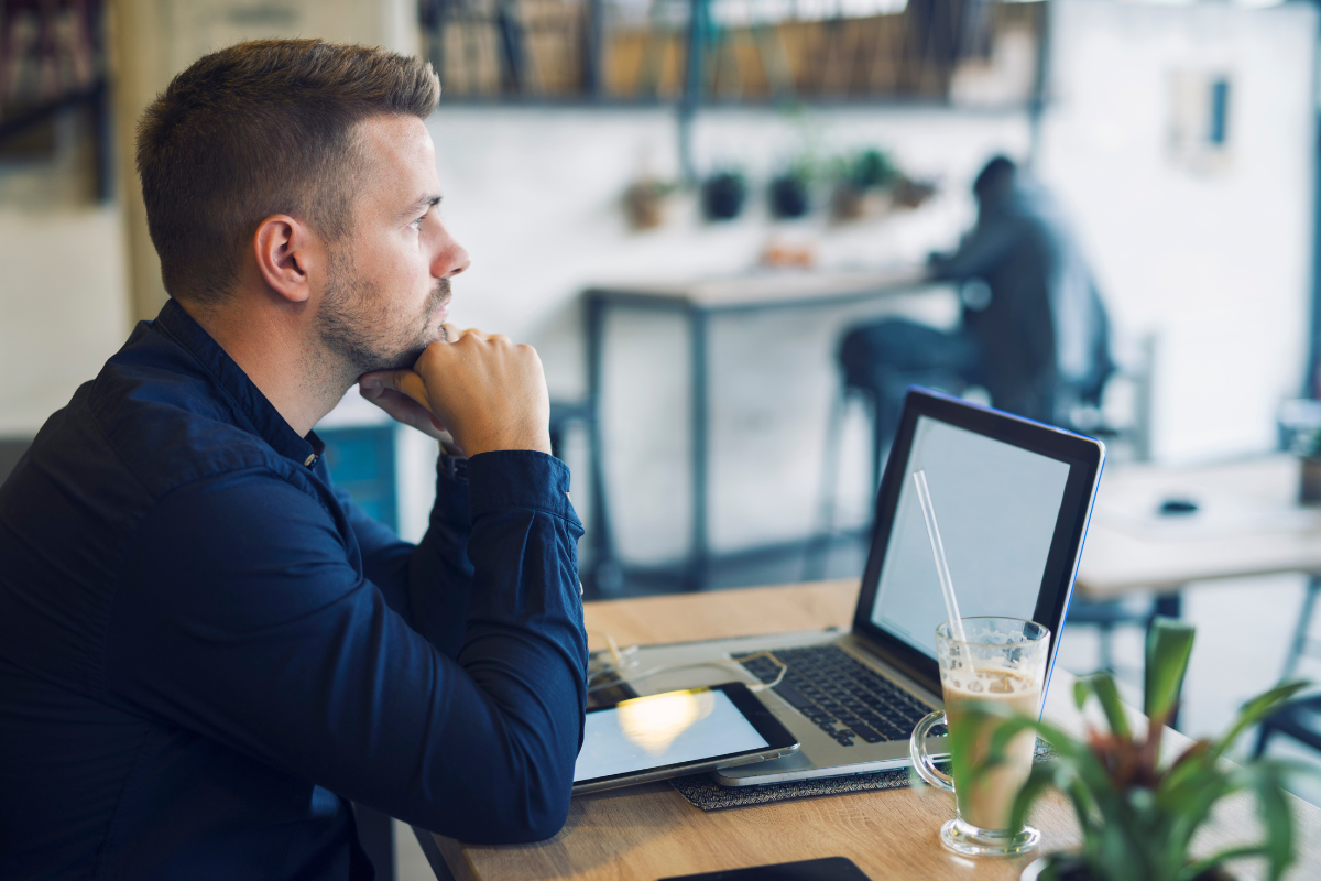 Homem em ambiente de escritório sentado lendo em um notebook sobre a mesa sobre o que é digitalização de documentos.