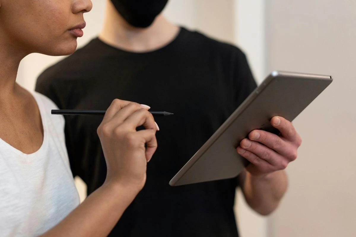 Um homem e uma mulher com tablete em mãos lendo e conversando sobre Documentos eletrônicos: o que são e por que são importantes.