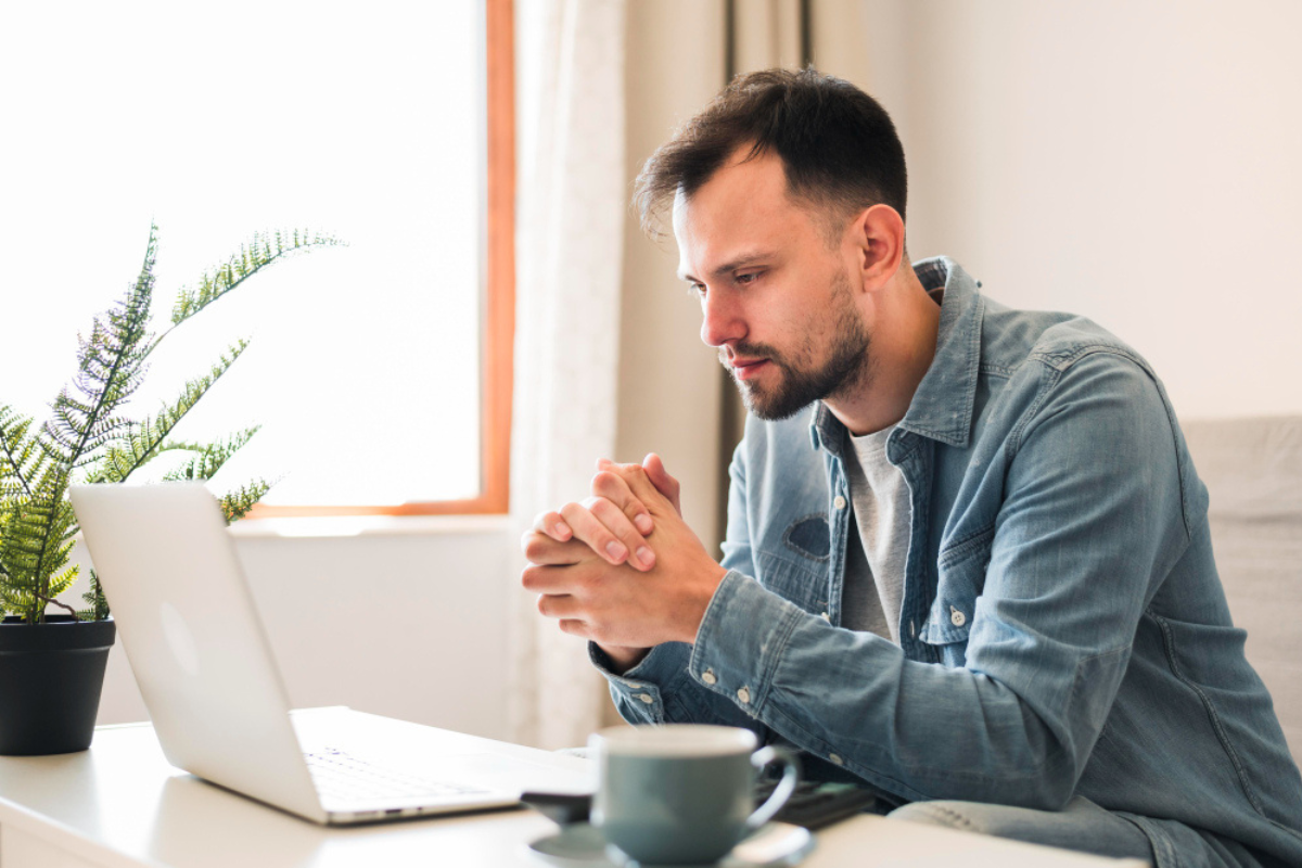 Homem em ambiente de escritório usando notebook representando: Qual a diferença entre assinatura digital e eletrônica.