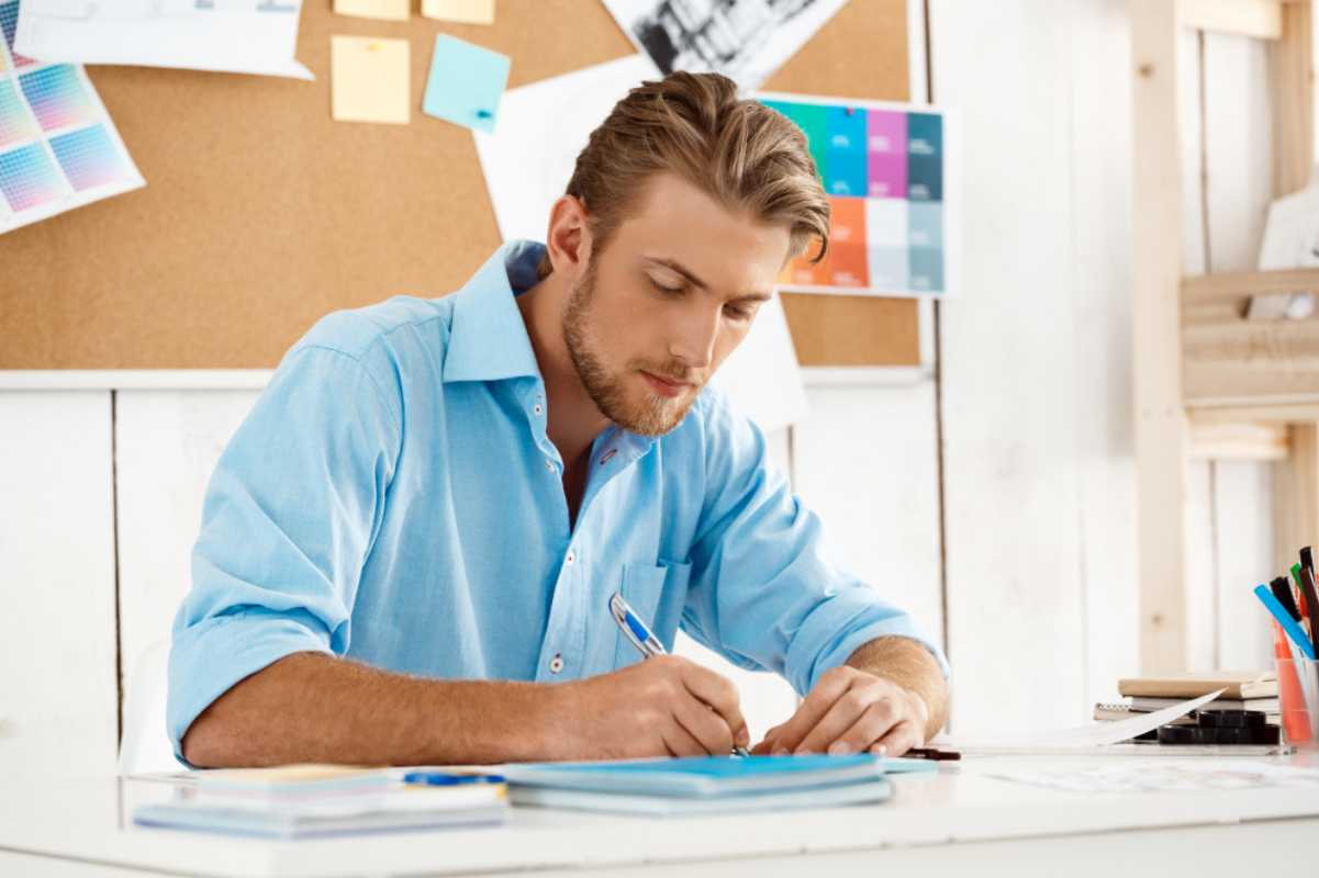 Homem em ambiente de escritório sentado assinando documentos sobre uma mesa representando: Rubrica: o que é, vantagens e como criar uma?